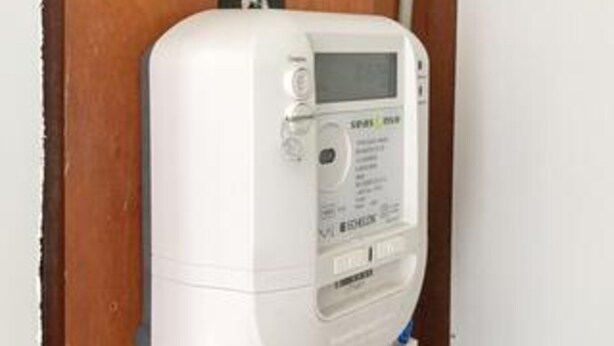 Un thermostat blanc, fixé au mur, doté d’un écran numérique, de boutons de commande et du nom de la marque.
