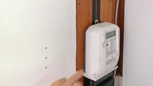 Une boîte électrique blanche, fixée au mur, avec un cadre de porte en bois.