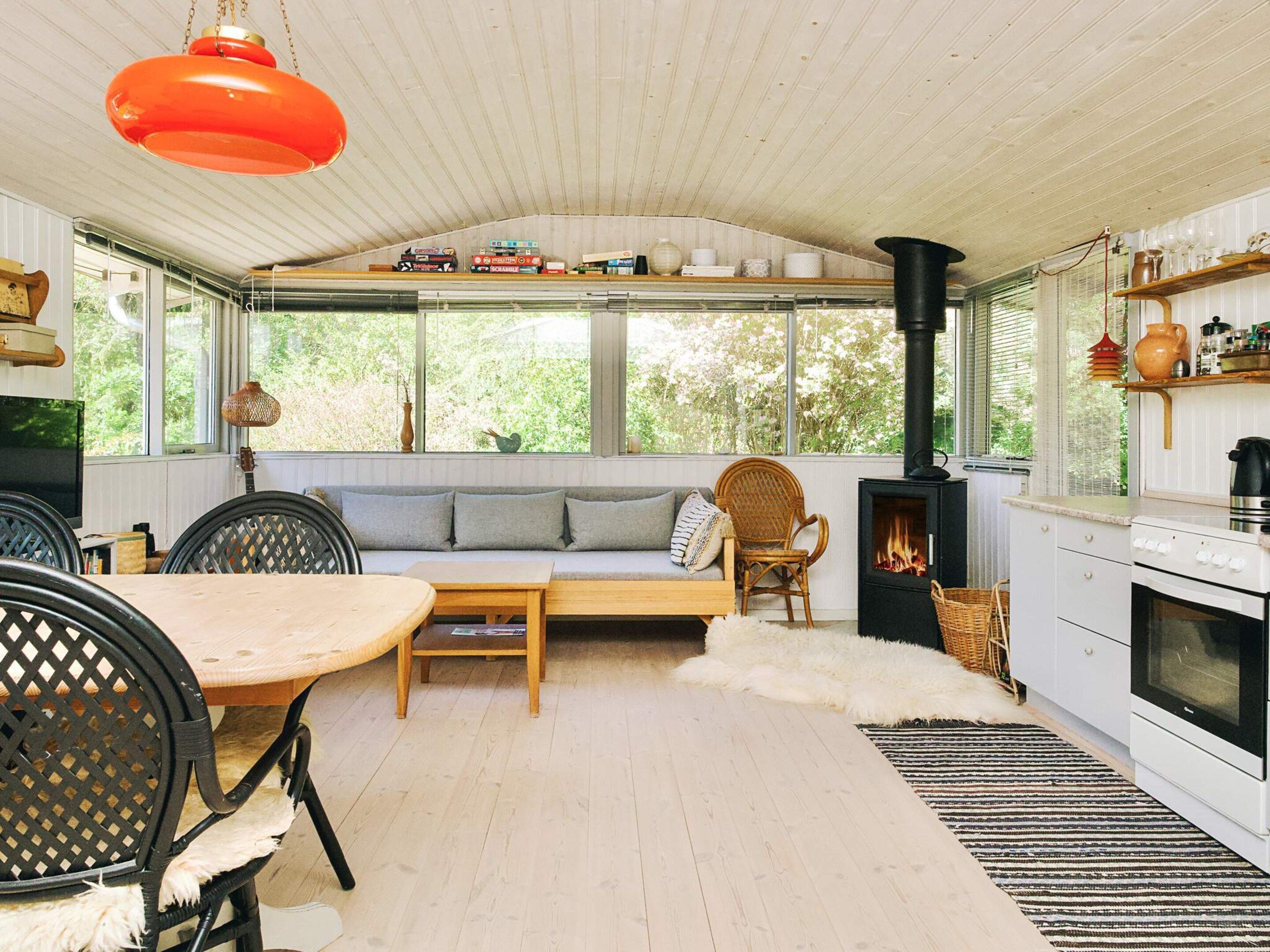 A cozy room with a sofa, chairs, a table, a fireplace, and a kitchen area.