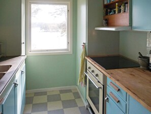 Een keuken met een raam, een fornuis en een spoelbak.