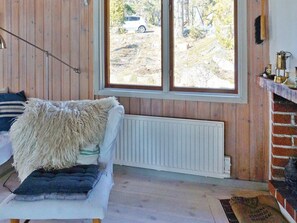 A cozy room with a white sofa, a fluffy throw, and a view of a parked car outside. - 6 Person Holiday Home in Djurhamn (Djurhamn)