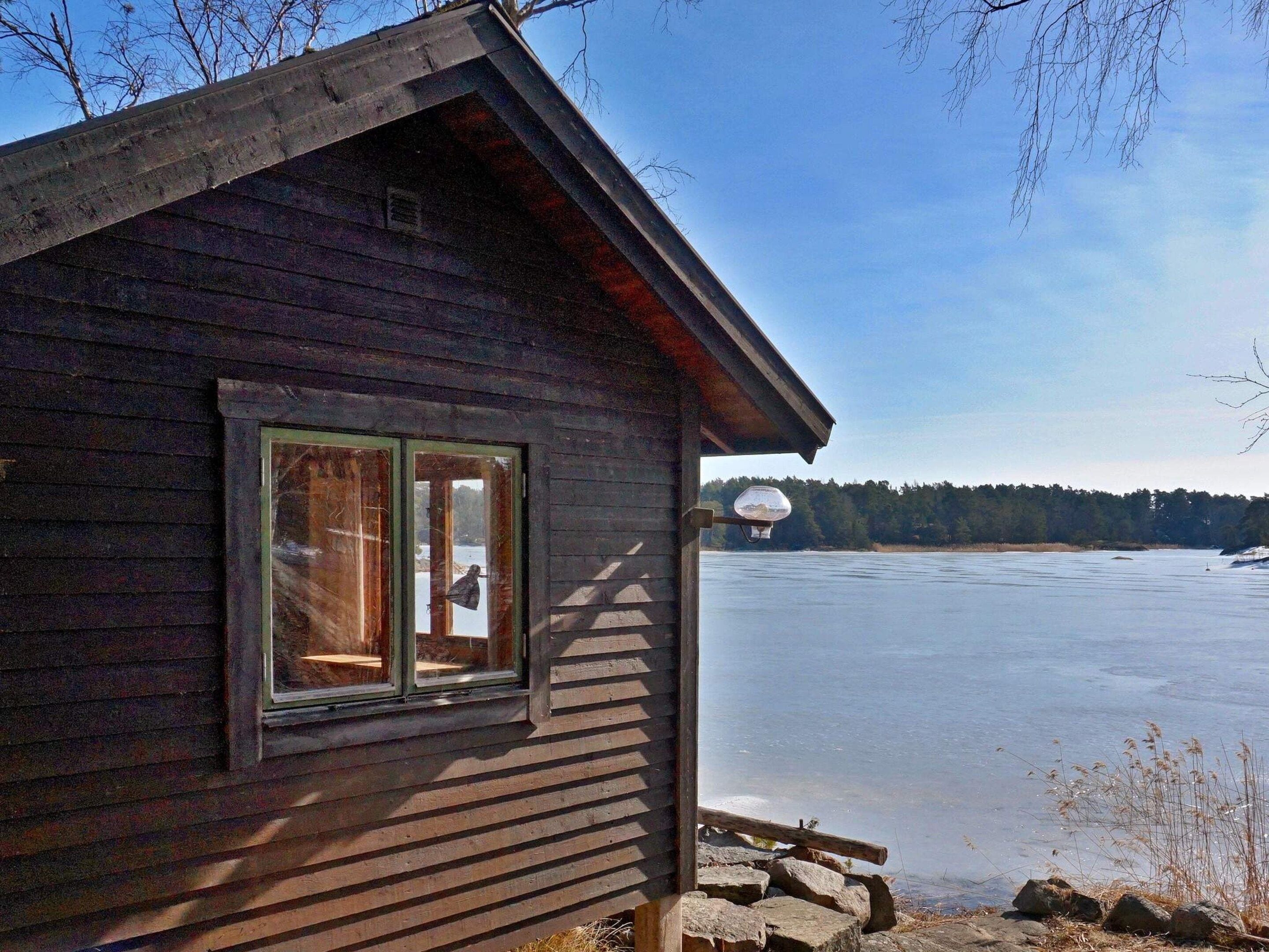 A wooden cabin with a window and a view of a frozen lake.