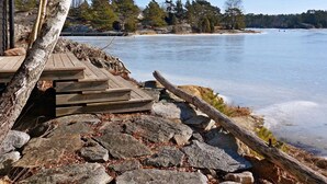 Un molo di legno che conduce a un lago ghiacciato, con alberi sullo sfondo e un cielo sereno.