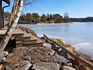 A wooden dock leading to a frozen lake with a backdrop of trees and a clear sky. - 6 Person Holiday Home in Djurhamn (Djurhamn)