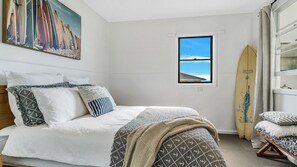 A bedroom with a bed, pillows, a window, and a surfboard. - Kokomo - Charming Coastal Escape (Wooli)