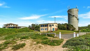 A coastal property with a large cylindrical structure, a two-story building, and a house with a sloped roof.