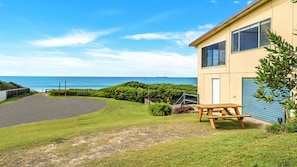 A coastal property with a paved driveway, a picnic table, and a view of the sea.