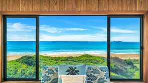 A room with a large window overlooking a beach and ocean.