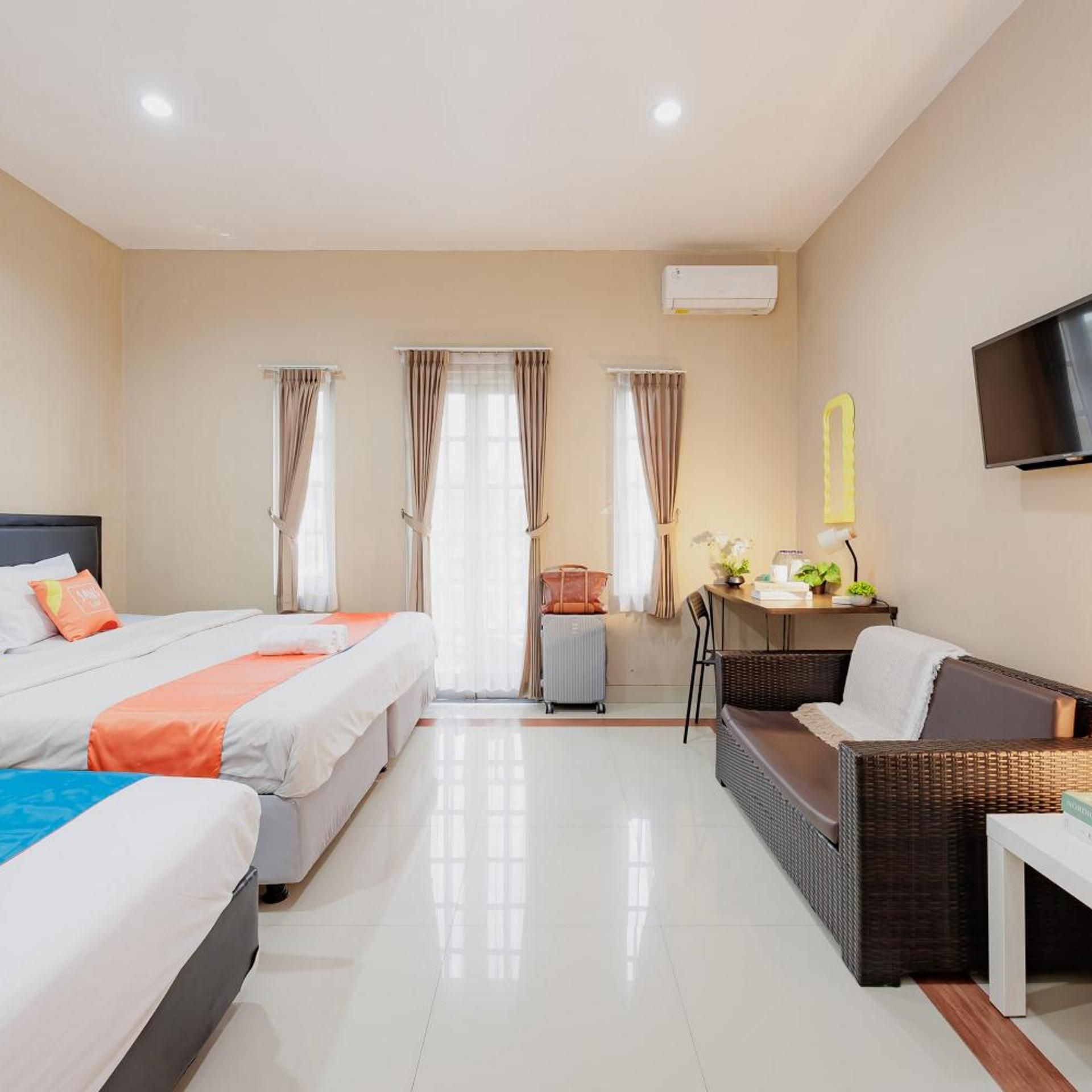 A hotel room with two beds, a sofa, a small table, and a TV.