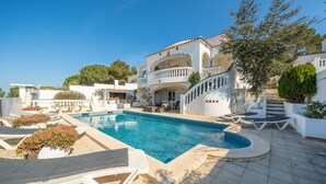 A pool area with lounge chairs and a large building with balconies. - Adriana: House with garden and private pool (L'Escala)