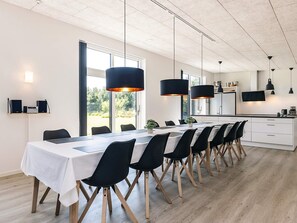 A modern dining area with a long table, black chairs, and pendant lights. - 5 Star Holiday Home in Vaeggerlose (Vaeggerlose)