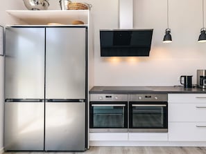A modern kitchen with a stainless steel refrigerator, a built-in oven, and a coffee maker on the counter.