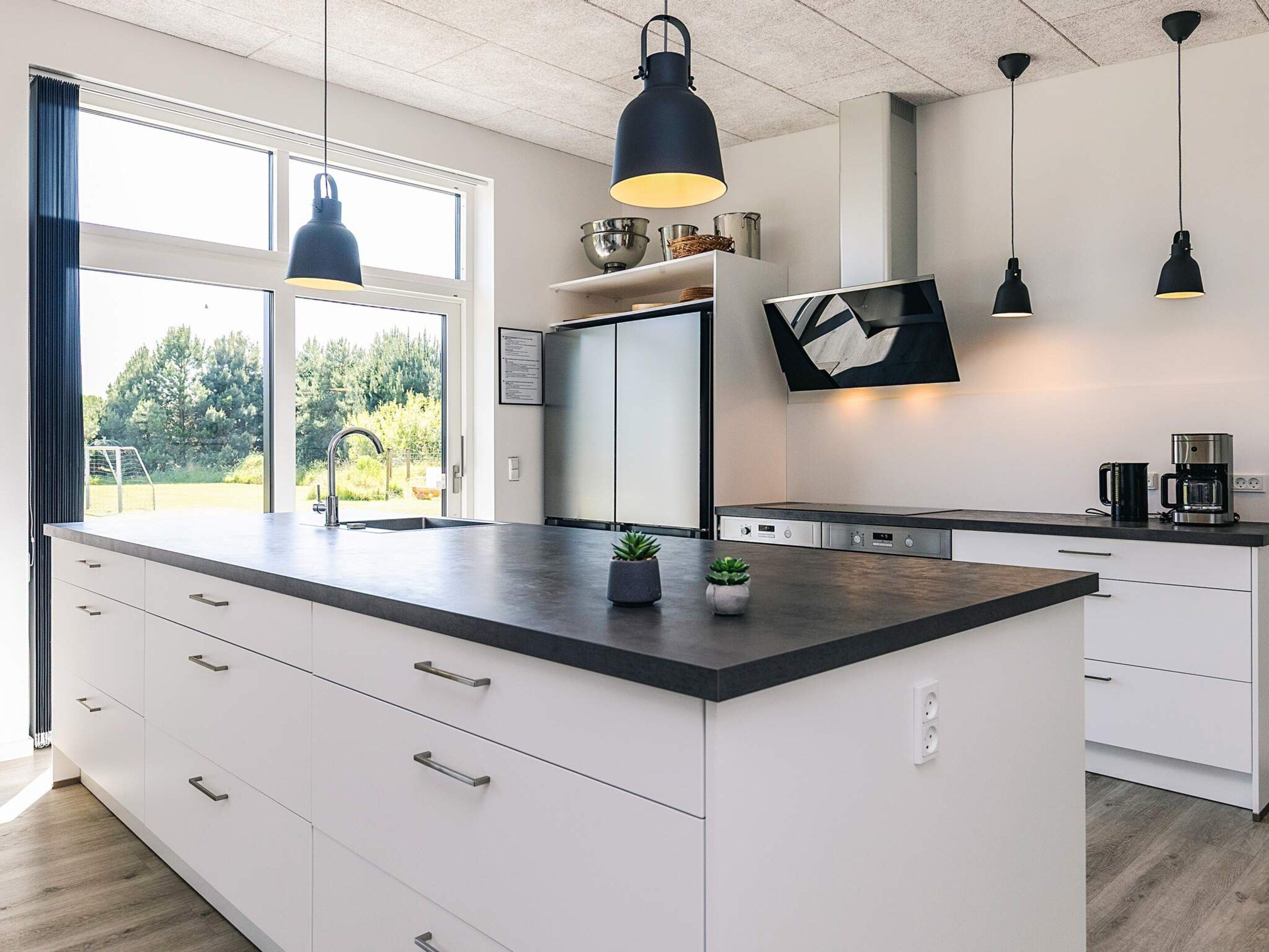 A modern kitchen with a central island, white cabinetry, and pendant lighting.