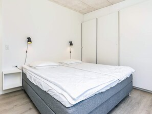 A bedroom with a bed, bedside tables, and wall-mounted lighting.
