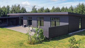A modern two-story building with a flat roof, large windows, and a covered outdoor seating area. - 5 Star Holiday Home in Vaeggerlose (Vaeggerlose)