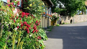 Een straat met een gebouw, voorzien van een tuin met verschillende bloemen en een stenen muur.
