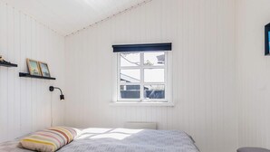 A bedroom with a bed, a window, a bedside lamp, and a bench.
