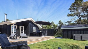 A black building with a deck, outdoor seating, and a metal fire pit.