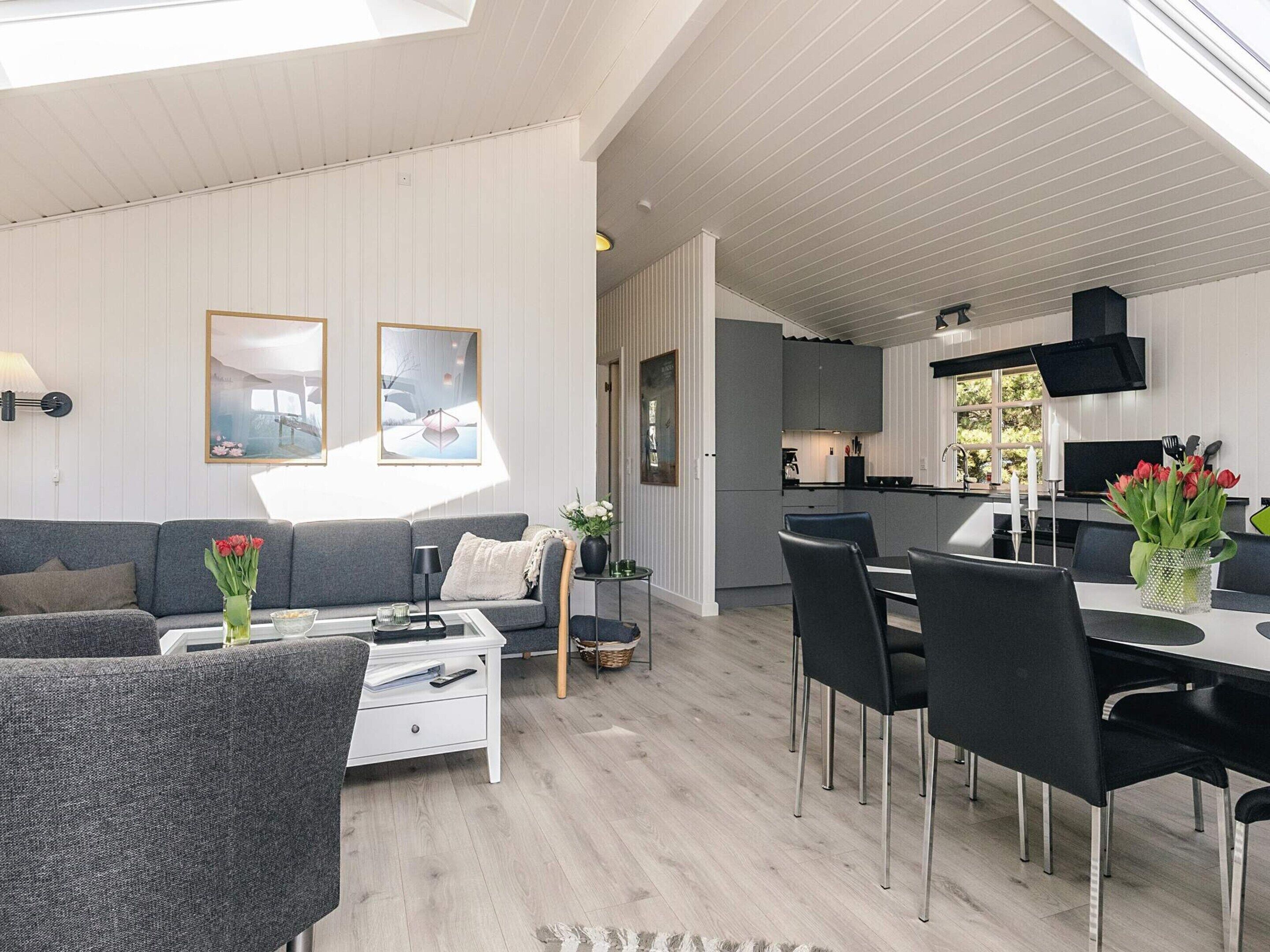 A modern interior with a sofa, dining table, and chairs, a kitchen area, and artwork on the walls.