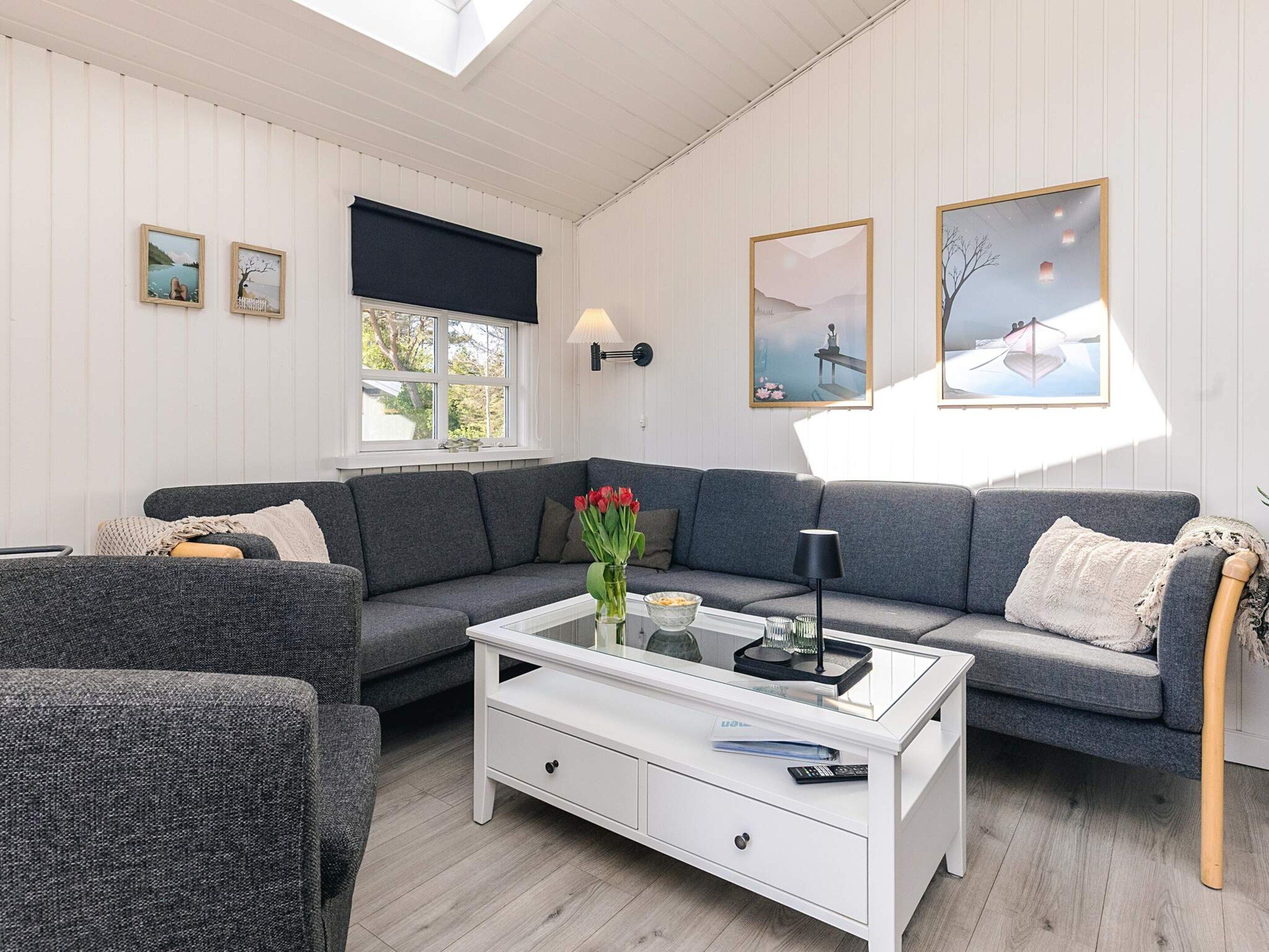 A modern living room with a grey sofa, a white coffee table, and artwork on the walls.