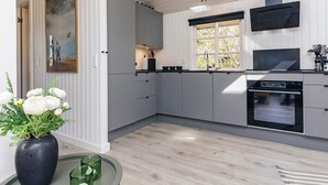 A modern kitchen with grey cabinets, a black stove, and a window with a view of greenery.