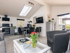 A modern kitchen with a dining area, a flat-screen TV, and a cozy seating area with a table and chairs.