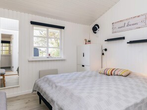 A bedroom with a bed, a window, a wardrobe, and a wall-mounted sign.