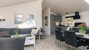 En moderne stue med sofa, sofabord og spiseplads.