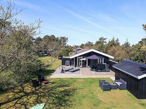 Uma casa moderna com varanda, móveis de exterior e chaminé.