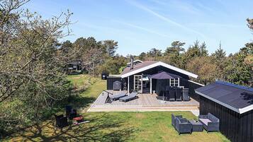 Et moderne hus med terrasse, udendørs møbler og en overdækket patio.