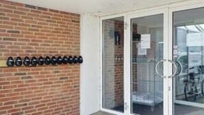 A brick wall with a row of black objects, a glass door with a metal handle, and a white door frame. - 4 Star Holiday Home in Ringkobing (Ringkobing)