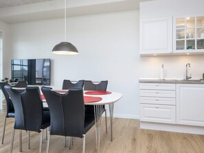 A modern kitchen with white cabinets, a dining area with black chairs and a round table, and a pendant light above the table.