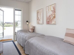 Een slaapkamer met twee bedden, een nachtkastje, een lamp en een kunstwerk aan de muur.