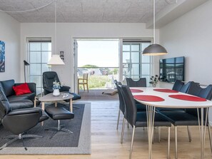 Ett modernt vardagsrum med en matplats, inrett med en soffa, stolar, ett bord och ett stort fönster.