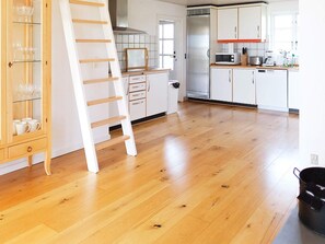 Eine Küche mit Holzboden, weißen Schränken, einem Edelstahlkühlschrank und einer Mikrowelle.