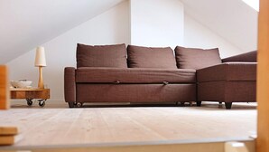 Un dormitorio tipo loft moderno con un sofá seccional marrón, una mesita de madera y una lámpara.