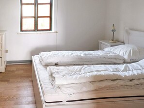 A bedroom with two beds, a nightstand, a lamp, and a window.