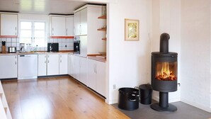 Una cocina moderna con armarios blancos, estufa y comedor con mesa de madera.
