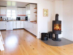 A modern kitchen with white cabinets, a stove, and a dining area with a wooden table. - 8 Person Holiday Home in Veslos (Vesløs)
