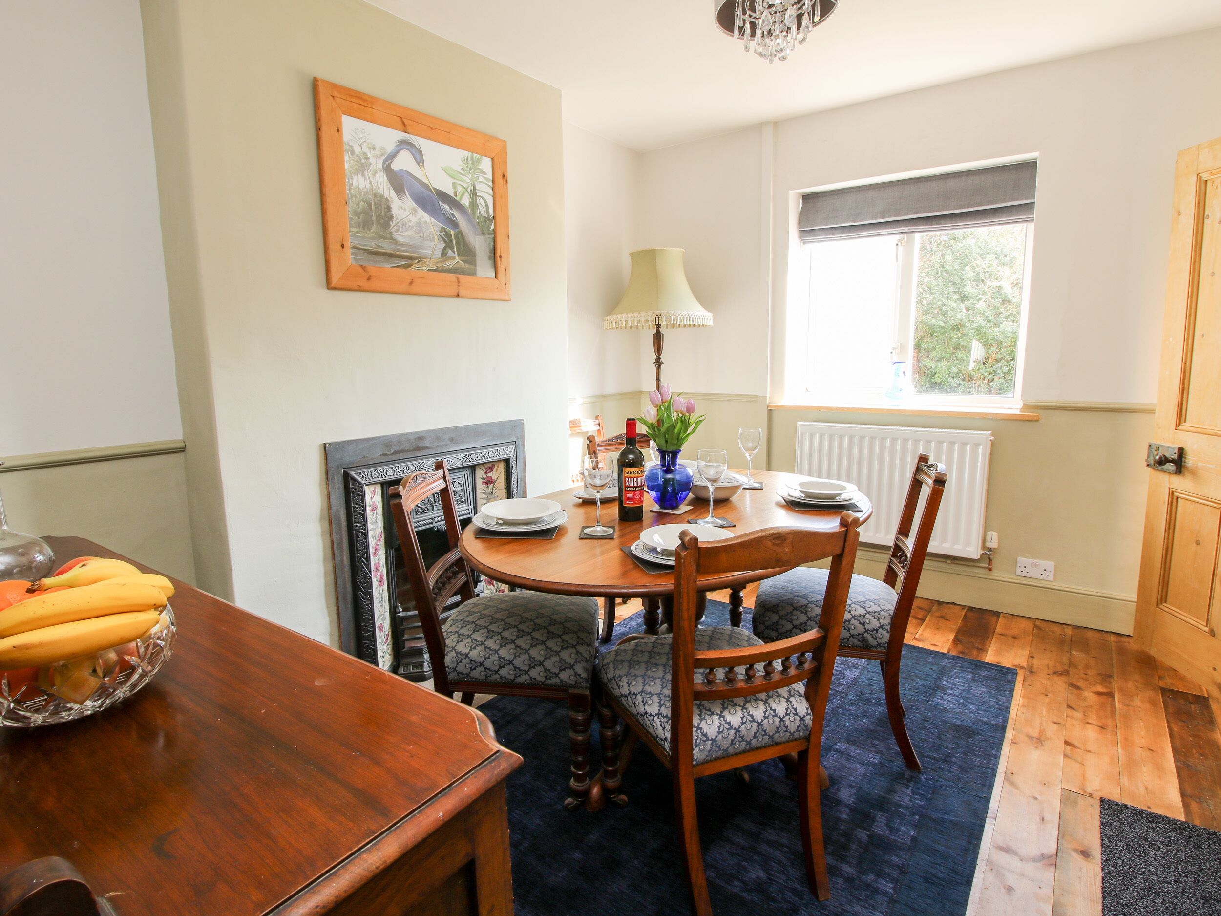 A dining area with a wooden table, chairs, and a fruit bowl.