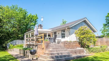 A two-story house with a covered porch, a barbecue grill, and a fenced yard.