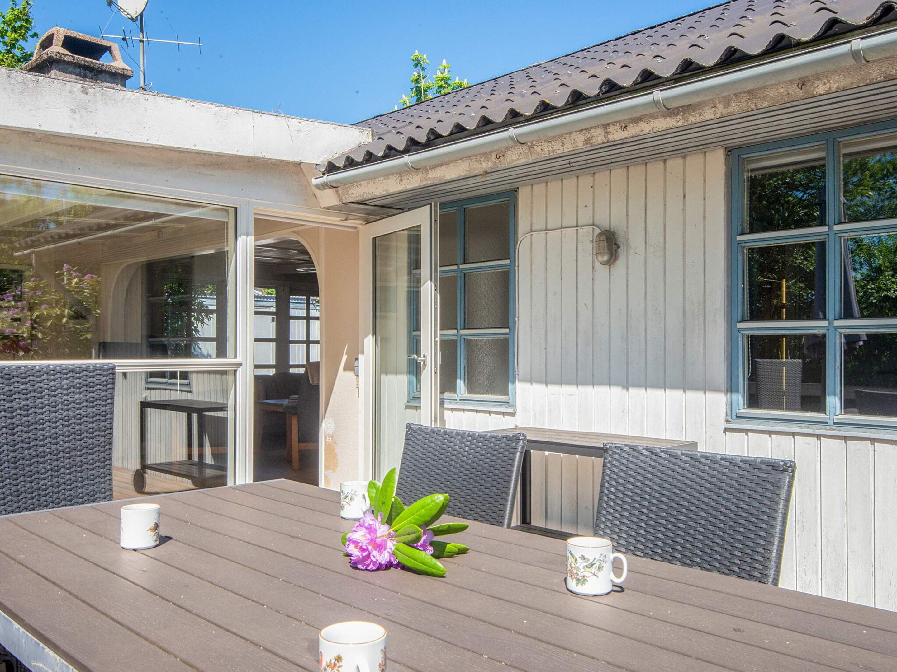 An outdoor dining area with a table, chairs, and two mugs.