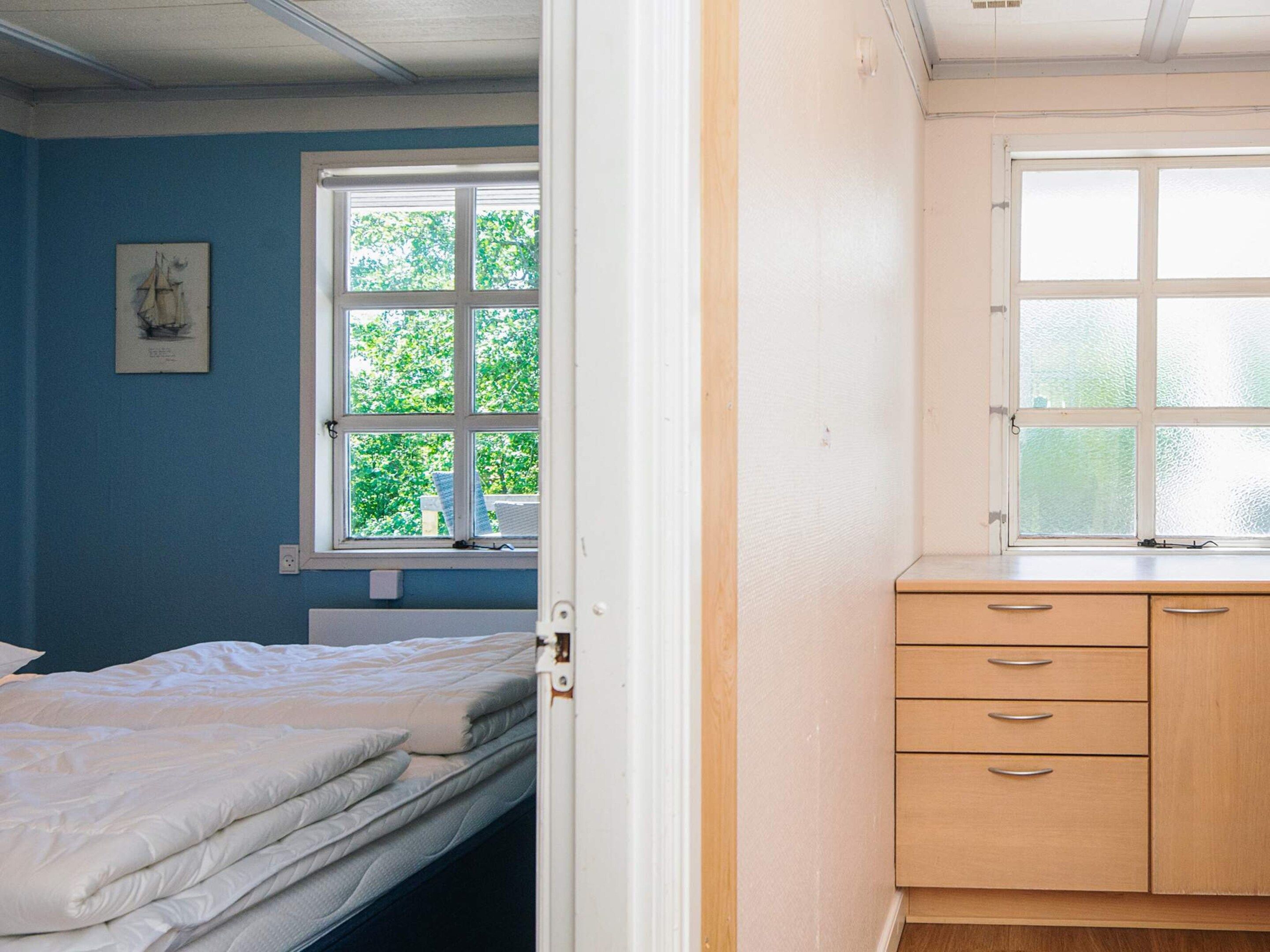 A bedroom with a bed, a window, and a wooden dresser.