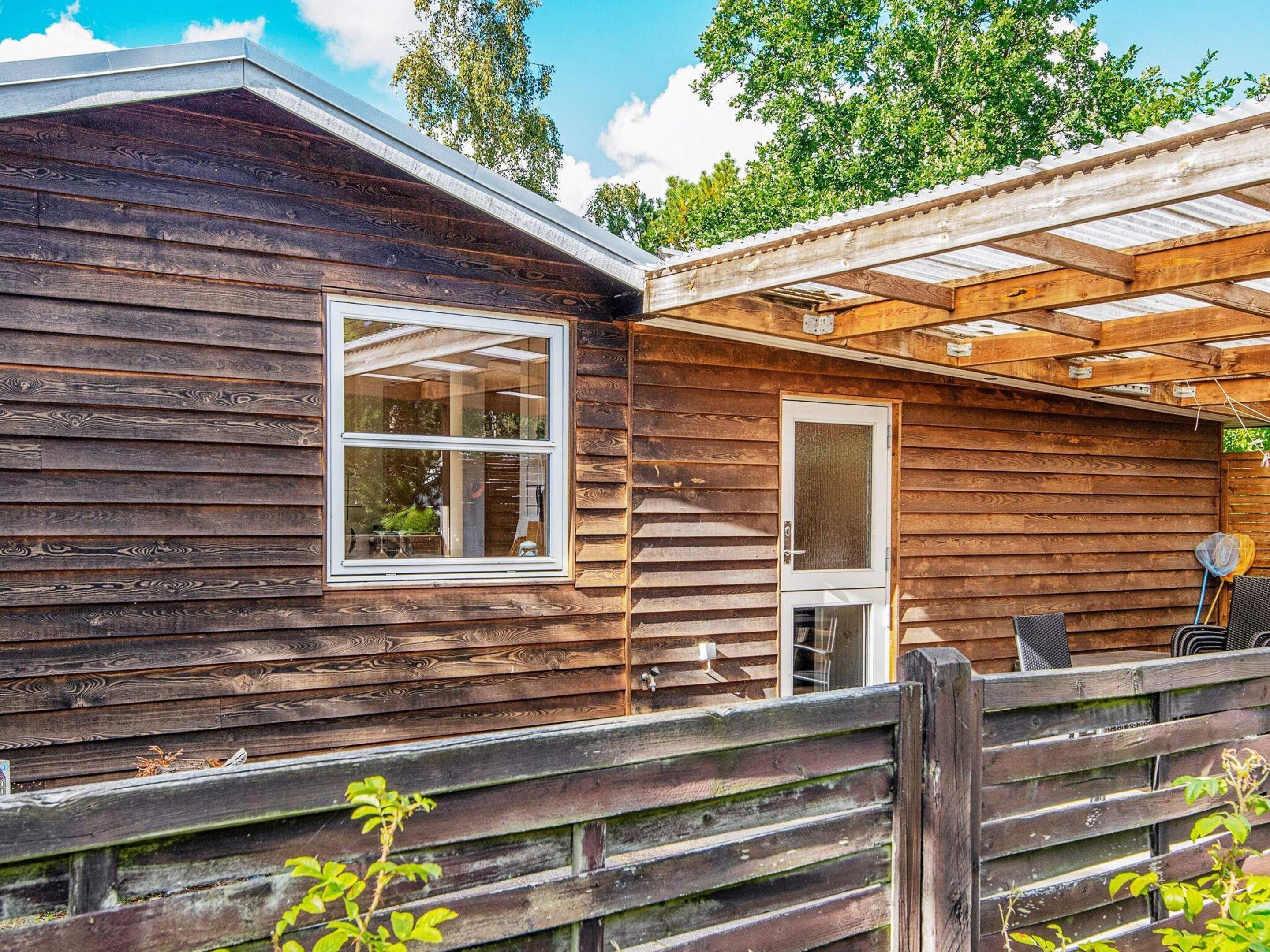 Una cabaña de madera con ventana, puerta y un porche cubierto.