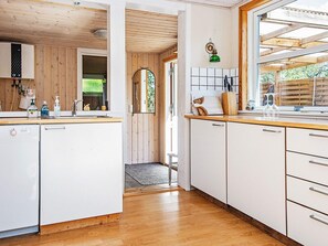 A kitchen with white cabinets, a wooden countertop, and a view of the outdoors through a window.