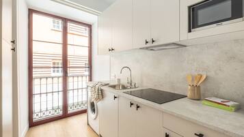 Una cucina moderna con forno a microonde integrato, lavandino e finestra con vista su un balcone.