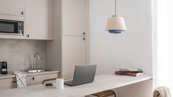 A modern kitchen with a laptop, a microwave, and a hanging light fixture.