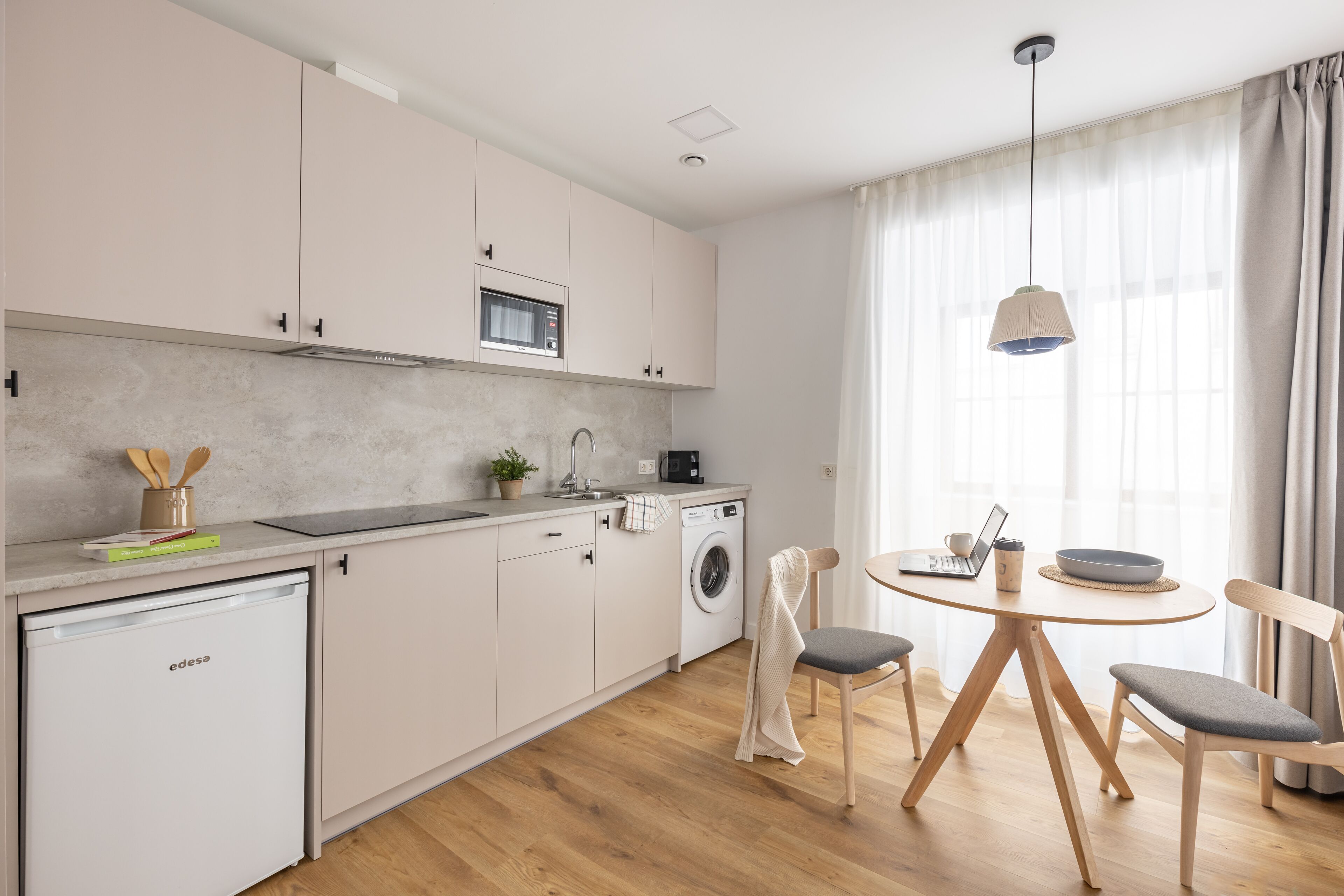 Una cocina moderna equipada con lavavajillas, lavadora y comedor con mesa y sillas.