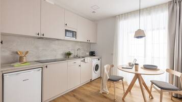 Una cocina moderna equipada con lavavajillas, lavadora y comedor con mesa y sillas.