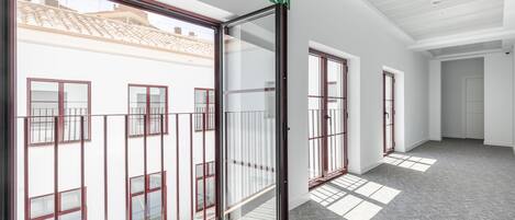 Un pasillo con amplios ventanales, una puerta de cristal e iluminación empotrada en el techo.